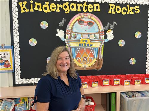 Mrs. Walker in classroom near bulletin board that reads Kindergarten Rocks.