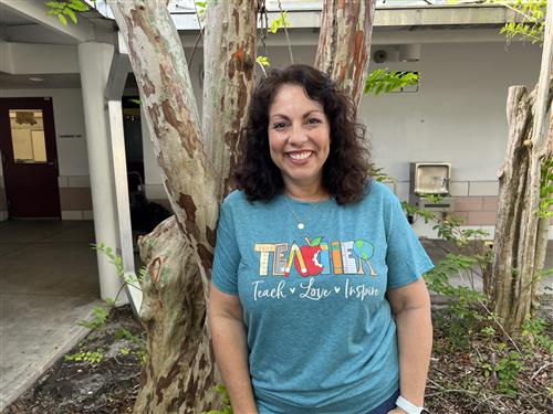 Mrs. Judd in first grade courtyard wearing a green T shirt that reads Teacher, Teach, Love, and Inspire