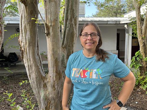 Mrs. Rossi in first grade courtyard wearing a green T shirt that reads Teacher, Teach, Love, and Inspire