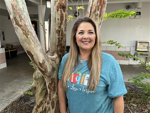 Mrs. Salbe in first grade courtyard wearing a green T shirt that reads Teacher, Teach, Love, and Inspire