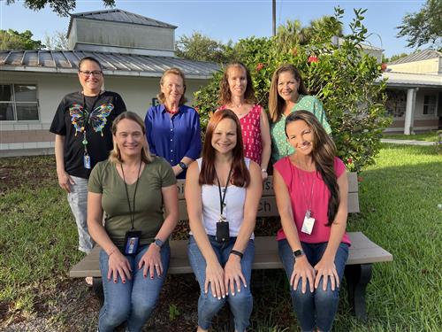 Third grade teachers sitting outside on a bench in the courtyard