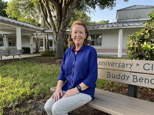 Mrs Gurrey sitting outside on a bench in the courtyard