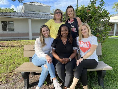 Fourth grade teacher Ms Cohen, Ms McCarthy, Ms Dionne, Mrs. Dyer, and Ms. Purcell sitting on a bench in the courtyard