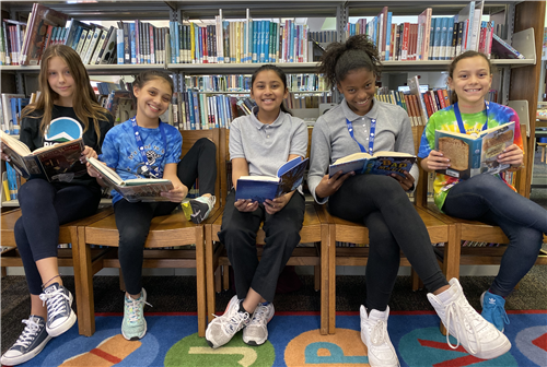 Students in front of book shelves with books 