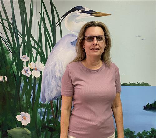 Ms. Edelman standing by mural of a heron