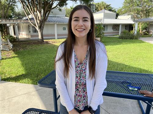 Ms. Granados standing in courtyard in front of blue picnic bench