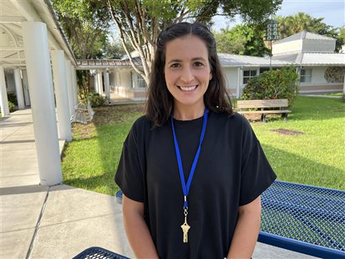 Ms. Ndjolba outside in the courtyard standing near a picnic table.