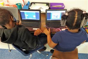 Two students working on an assignment on their computers.