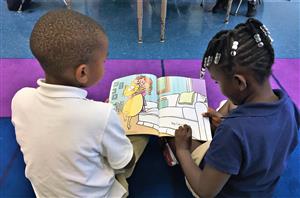 Two students reading a book.