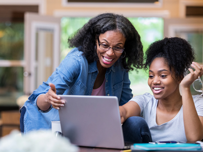A mother looking at computer work with her daughter at home 