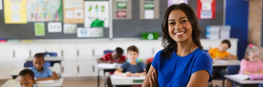 Teacher sitting in classroom smiling, students in the background