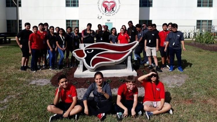 Students posing in the garden with donated cardinal statue.