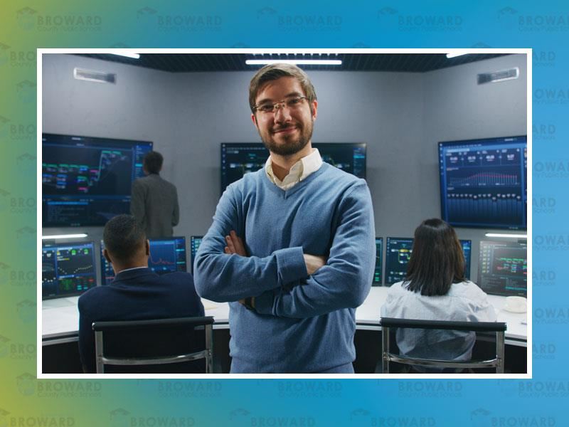 Cyber tech guy standing in a security room with monitors on the wall
