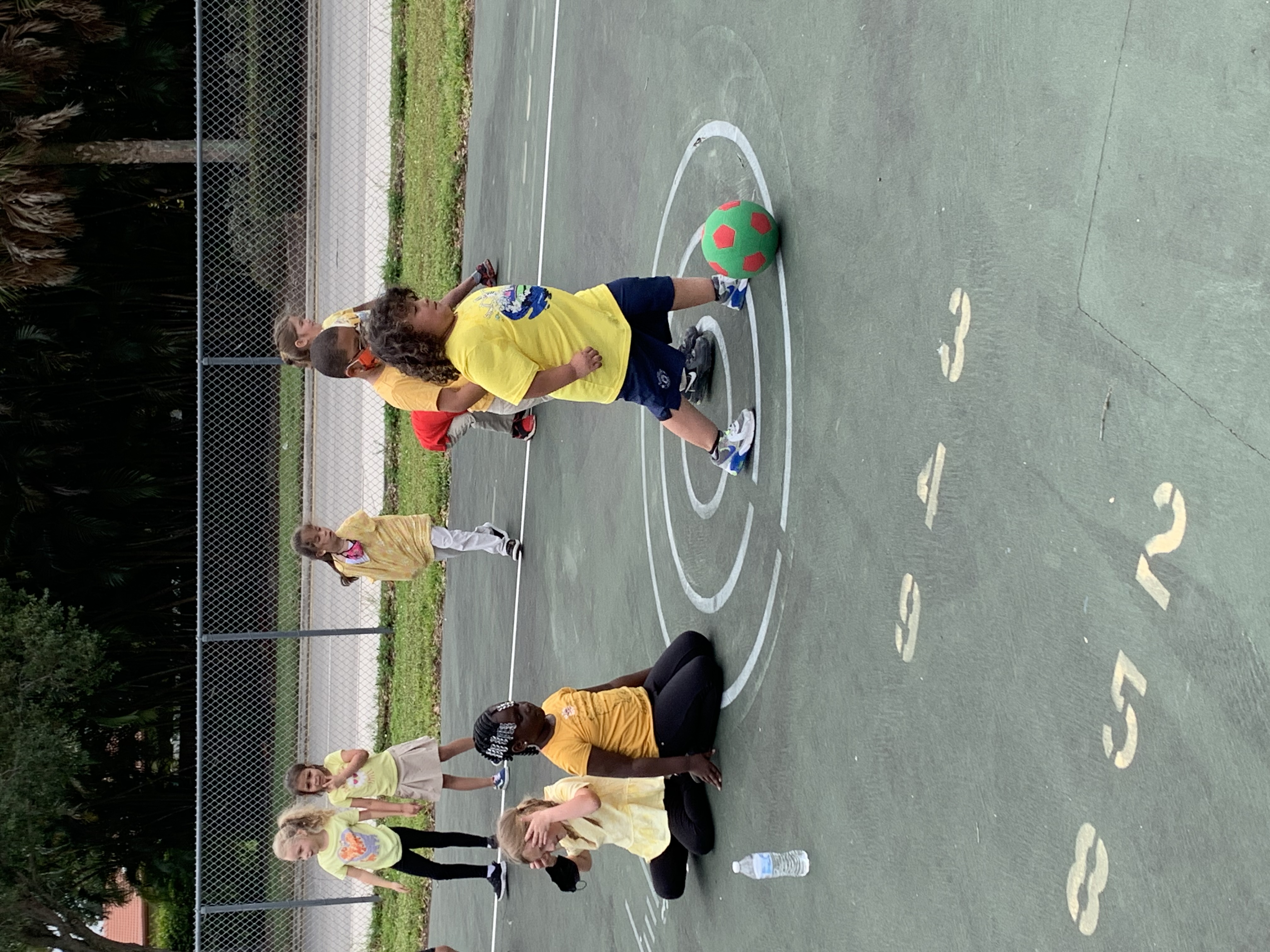 student in yellow shirt kicking a soccer ball