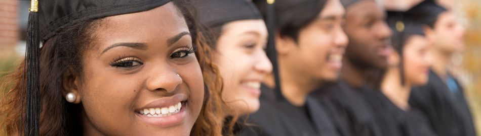 Students smiling in graduation cap and gown